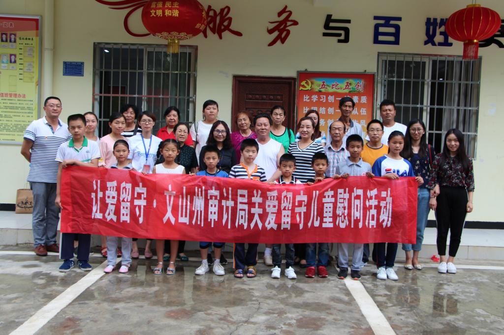 图为文山州审计局干部职工与卧龙社区留守儿童及家长合影