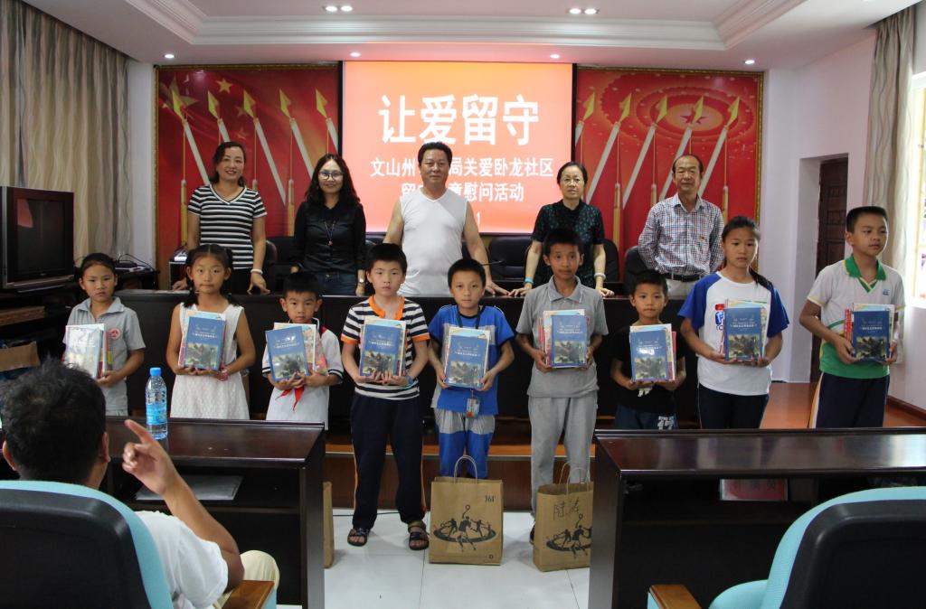 图为文山州审计局领导为留守儿童赠送图书和衣服